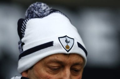 A Tottenham Hotspur fan wearing a hat with the club badge